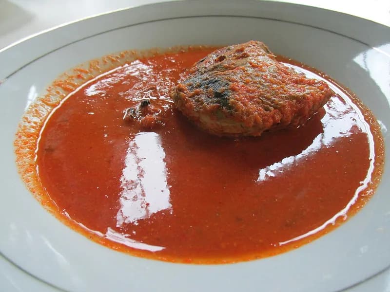 Sepotong ikan asam padeh dalam kuah merah cabai yang kental di piring putih