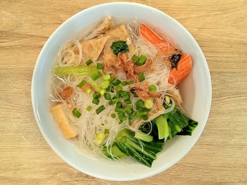 Semangkuk bihun kuah bening dengan sawi sendok, tahu, bakso ikan, dan bawang goreng