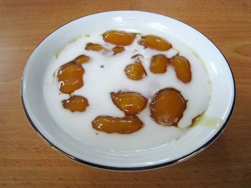 Semangkuk biji salak berwarna oranye kecokelatan dengan kuah gula merah dan siraman santan putih