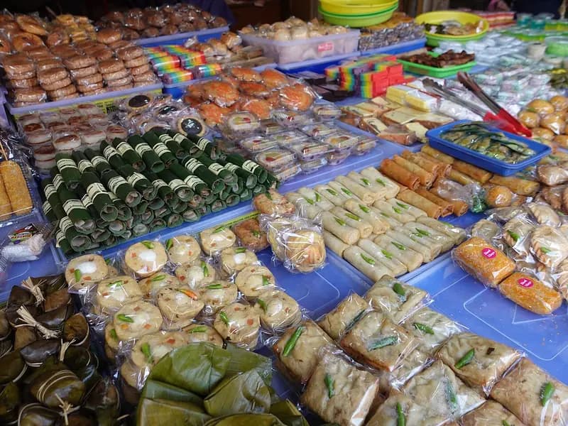 Aneka jajanan tradisional seperti lemper, kue lapis, bolu, dan kue bungkus daun di meja lapak