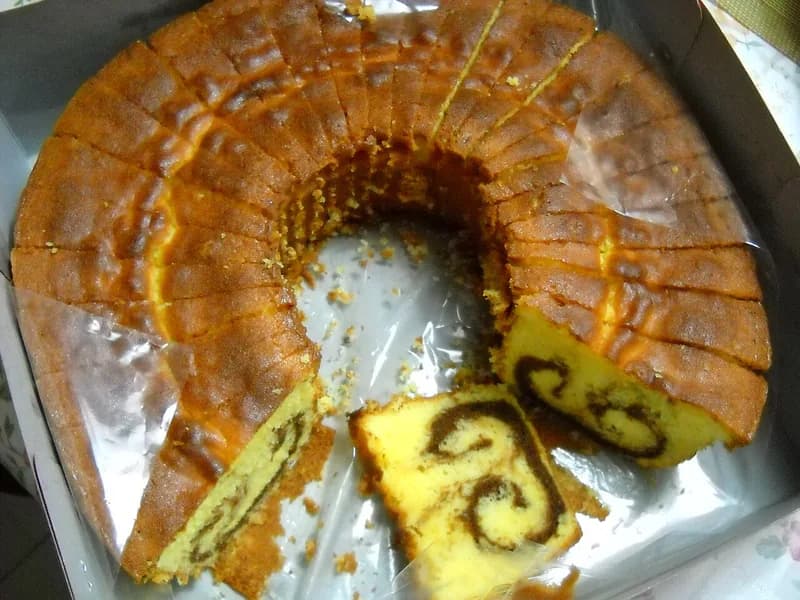 Kue bolu marmer panggang berbentuk cincin yang sudah dipotong, memperlihatkan pola cokelat di dalamnya