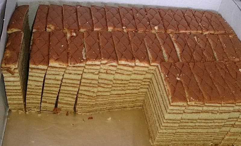 Potongan kue lapis legit dalam kotak memperlihatkan belasan lapisan tipis kuning dan cokelat