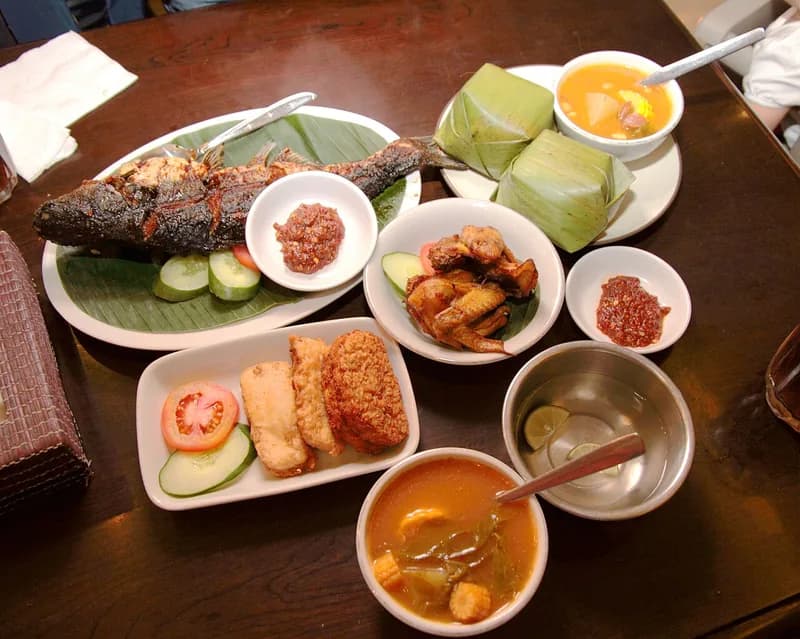 Hidangan Sunda di meja: ikan bakar, nasi timbel daun pisang, ayam goreng, tempe, sayur asem, dan sambal