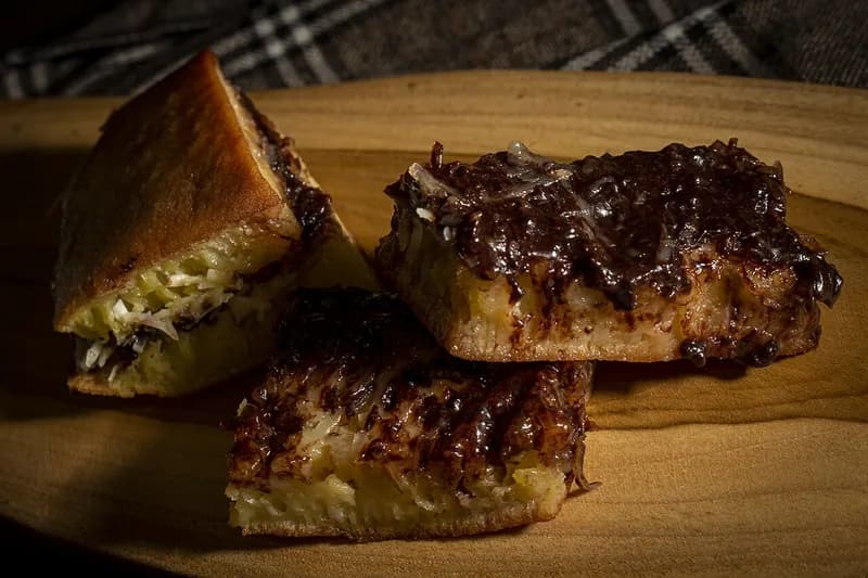 Potongan martabak manis tebal berisi cokelat dan keju dengan tekstur sarang di bagian dalam