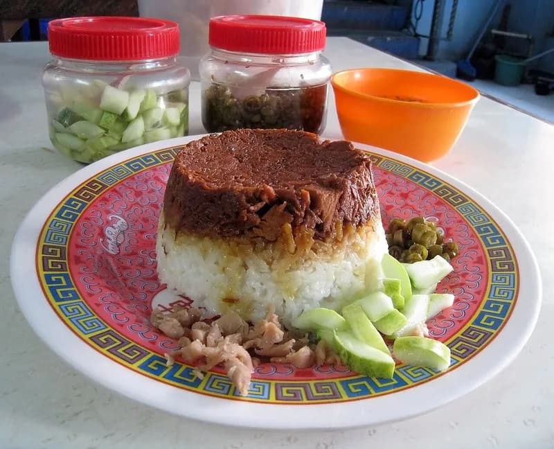 Nasi tim ayam cetak dengan lapisan ayam kecap di atas nasi putih, disajikan dengan acar timun