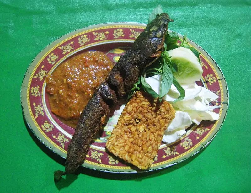 Sepiring pecel lele: lele goreng utuh, sambal, tempe goreng, kol, timun, dan daun kemangi