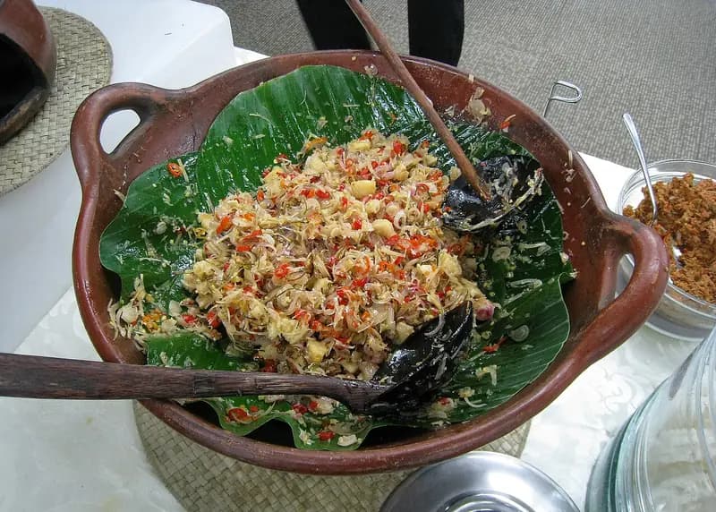 Sambal matah Bali berisi irisan bawang merah, serai, dan cabai rawit di atas daun pisang dalam cobek tanah liat