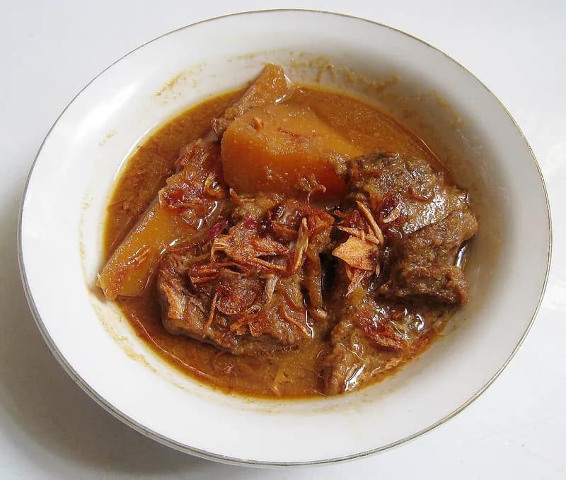 Semur daging sapi dengan potongan kentang dalam kuah kecap cokelat bertabur bawang goreng