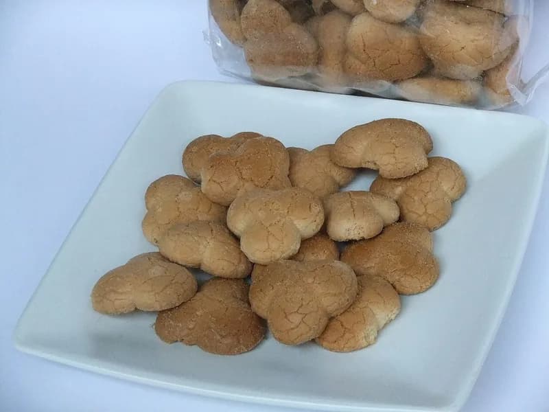 Kue bangkit dari tepung sagu berbentuk bunga dengan permukaan retak halus di piring putih