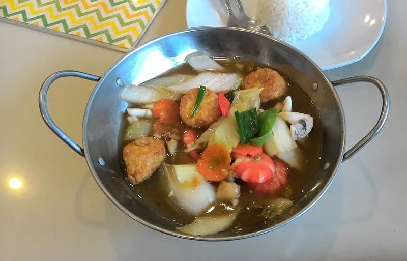 Sapo tahu berkuah kental dengan tahu goreng, udang, wortel, dan sawi putih dalam panci logam