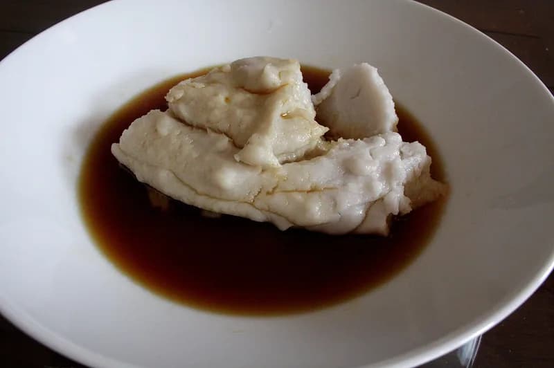 Bubur sumsum putih lembut dari tepung beras dalam piring putih bersiram kuah gula merah cair