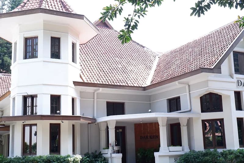 Fasad Cafe Dakken di Bandung, bangunan putih bergaya lama dengan atap genteng merah dan menara