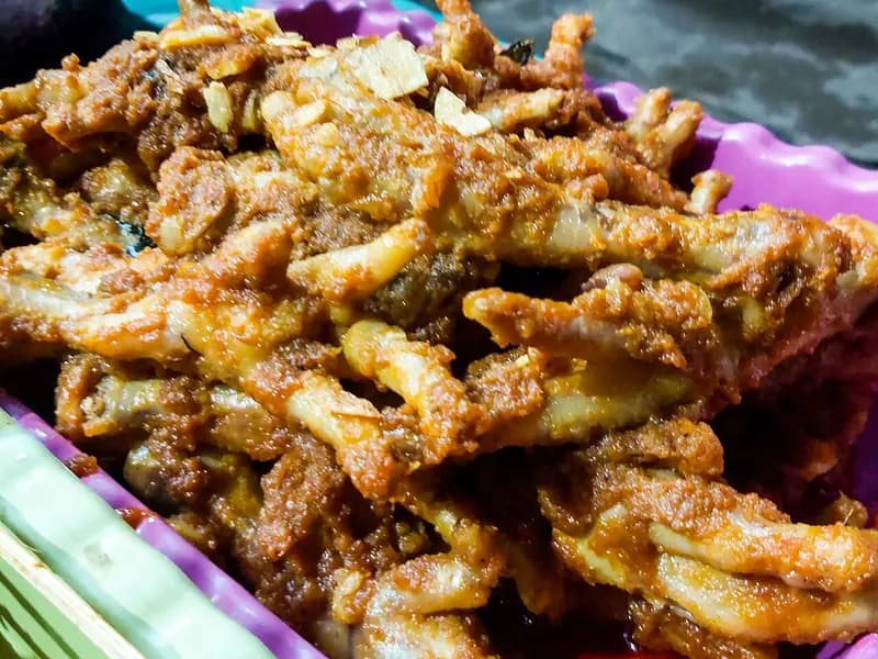 Tumpukan ceker ayam pedas berbalut bumbu cabai merah kental dengan taburan bawang goreng