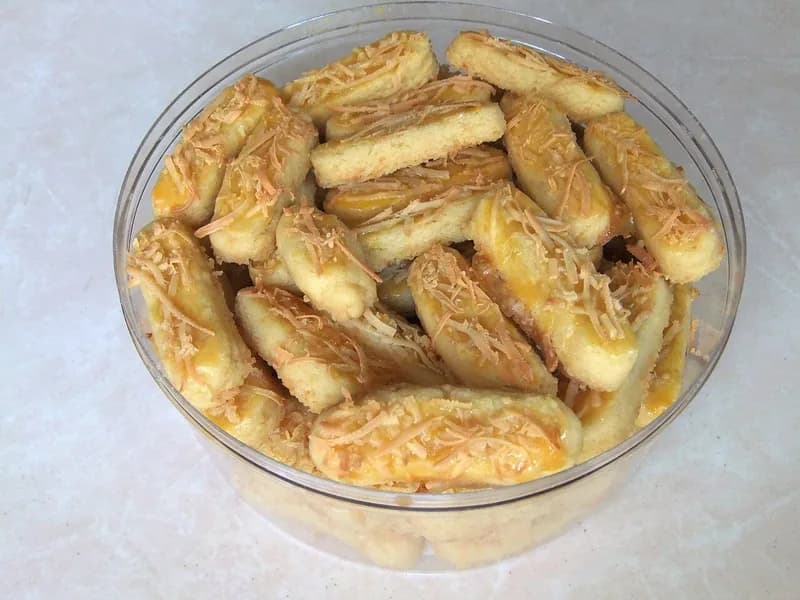 Kastengel batang keemasan bertabur parutan keju cheddar dalam toples plastik bening