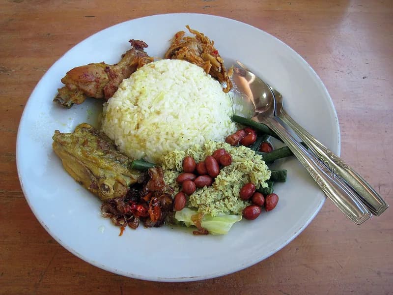 Sepiring nasi campur Bali dengan ayam betutu, sayur urap, kacang goreng, dan sambal di Denpasar