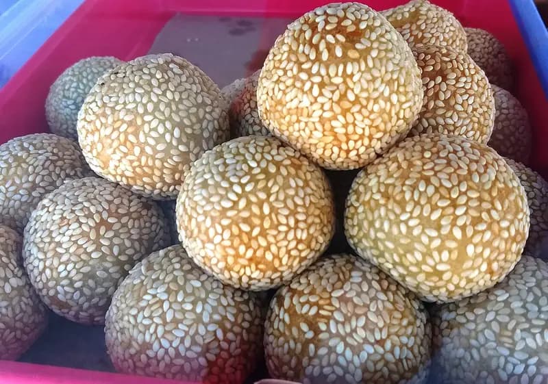Tumpukan onde-onde wijen bulat berwarna keemasan dengan taburan biji wijen putih yang rapat