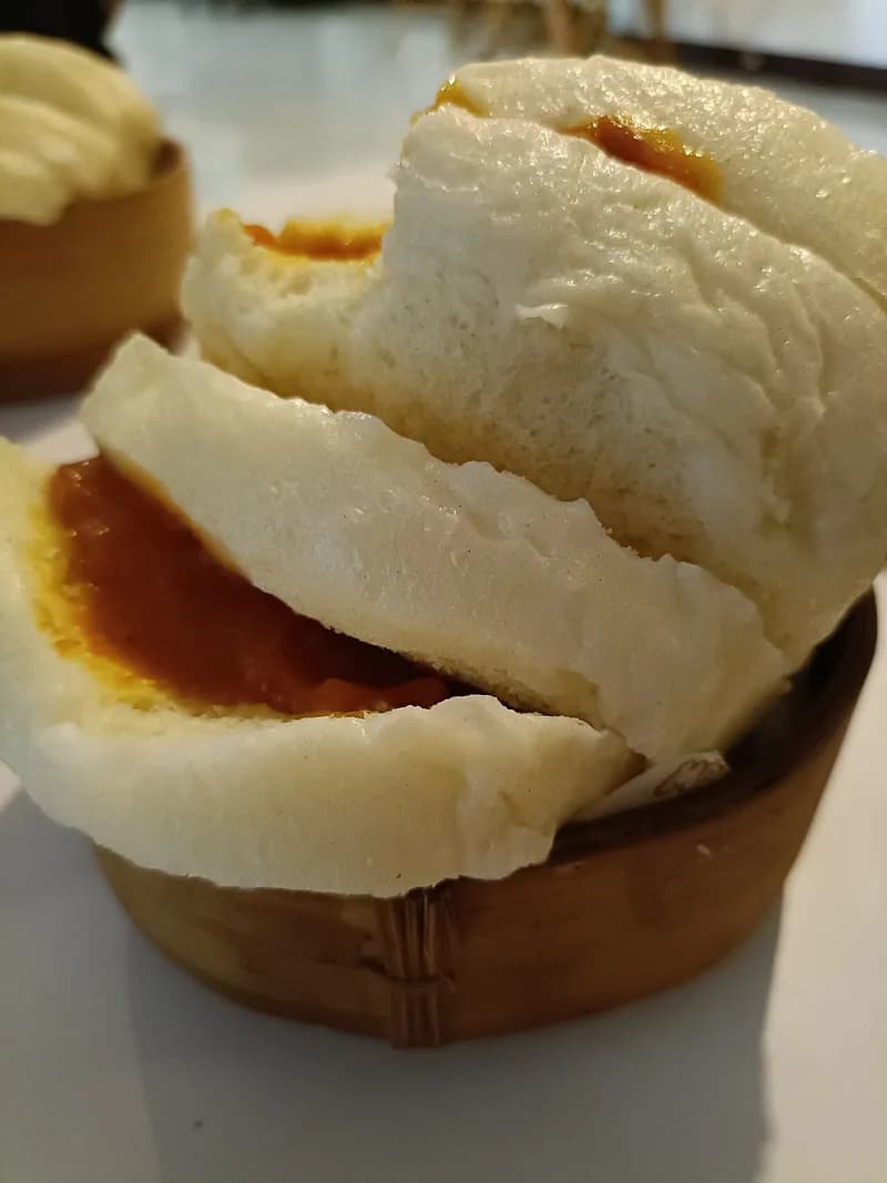 Roti kukus putih lembut diiris dan diolesi selai srikaya, disajikan dalam kukusan bambu