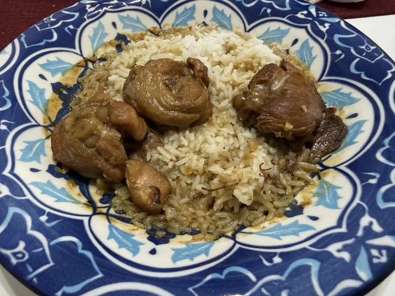 Potongan ayam masak kecap berwarna cokelat mengilap di atas nasi dalam piring bermotif biru