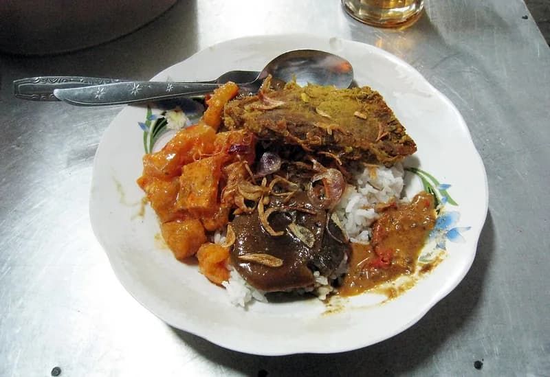 Nasi uduk dengan semur jengkol berkuah kecap cokelat gelap, empal daging, sambal goreng, dan bawang goreng