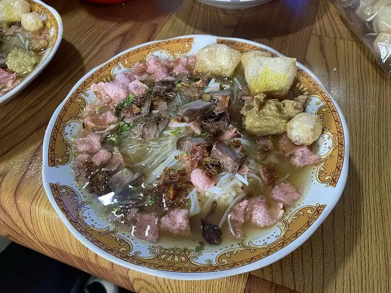 Sepiring soto Padang berkuah bening dengan bihun, daging goreng kering, perkedel, dan kerupuk merah