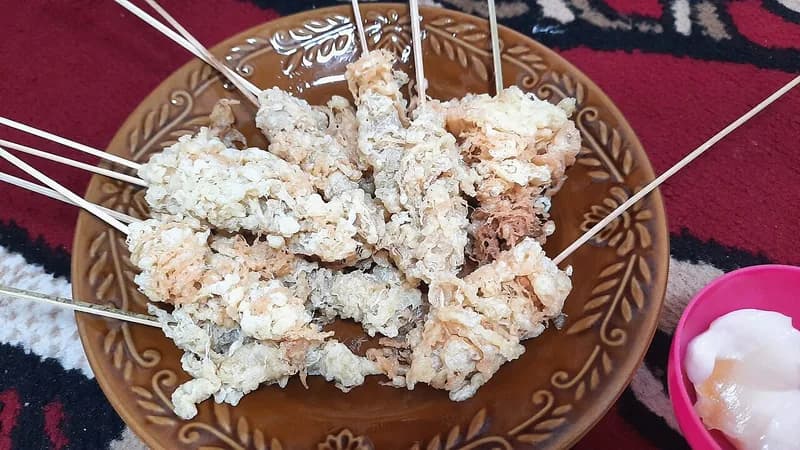 Sepiring telur gulung goreng bertusuk lidi dengan tekstur berserat renyah dan saus mayones