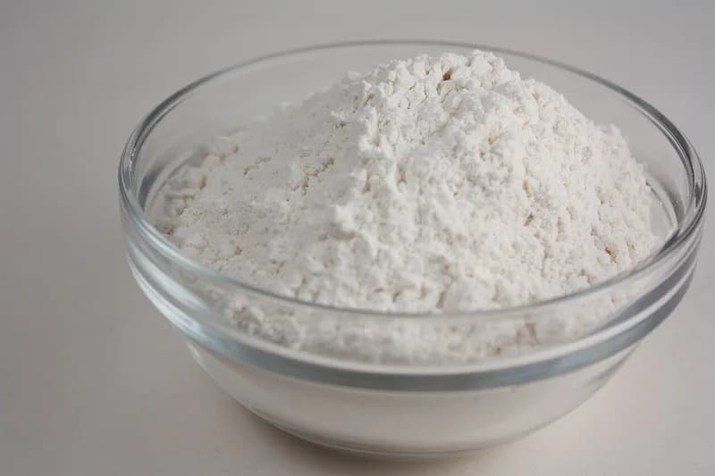 Tepung terigu putih halus menggunung di dalam mangkuk kaca bening