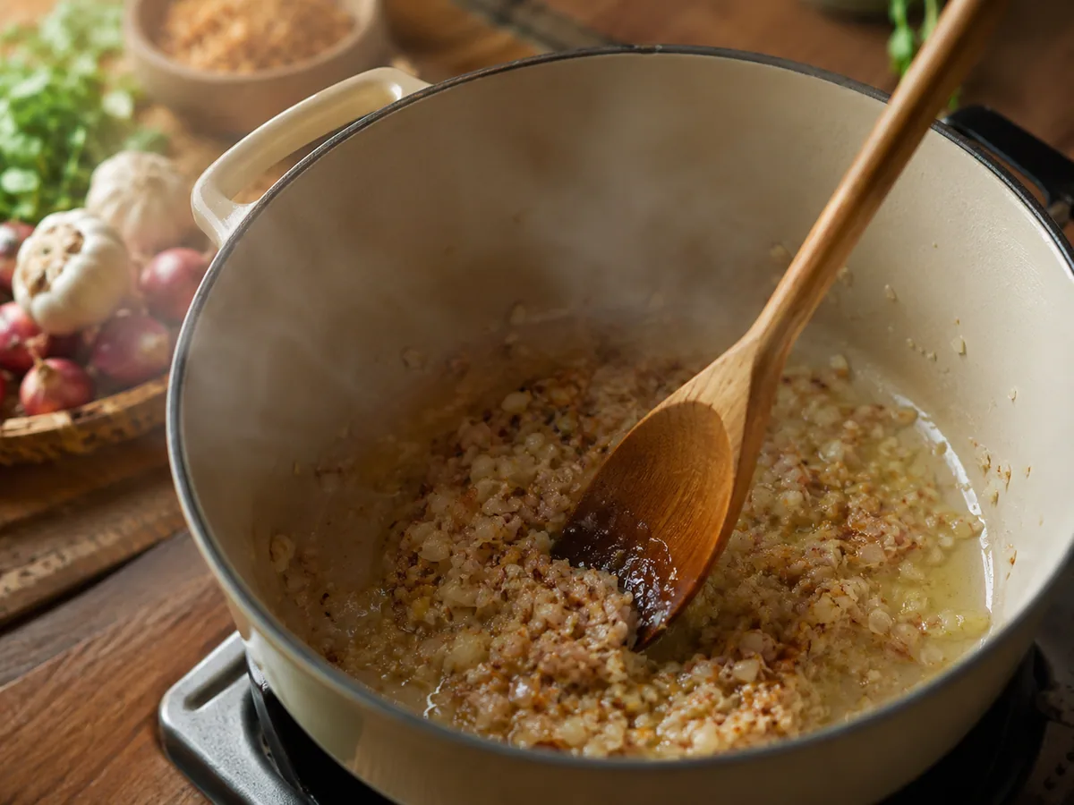 Proses menumis bumbu bawang untuk kuah mie rebus di dalam panci