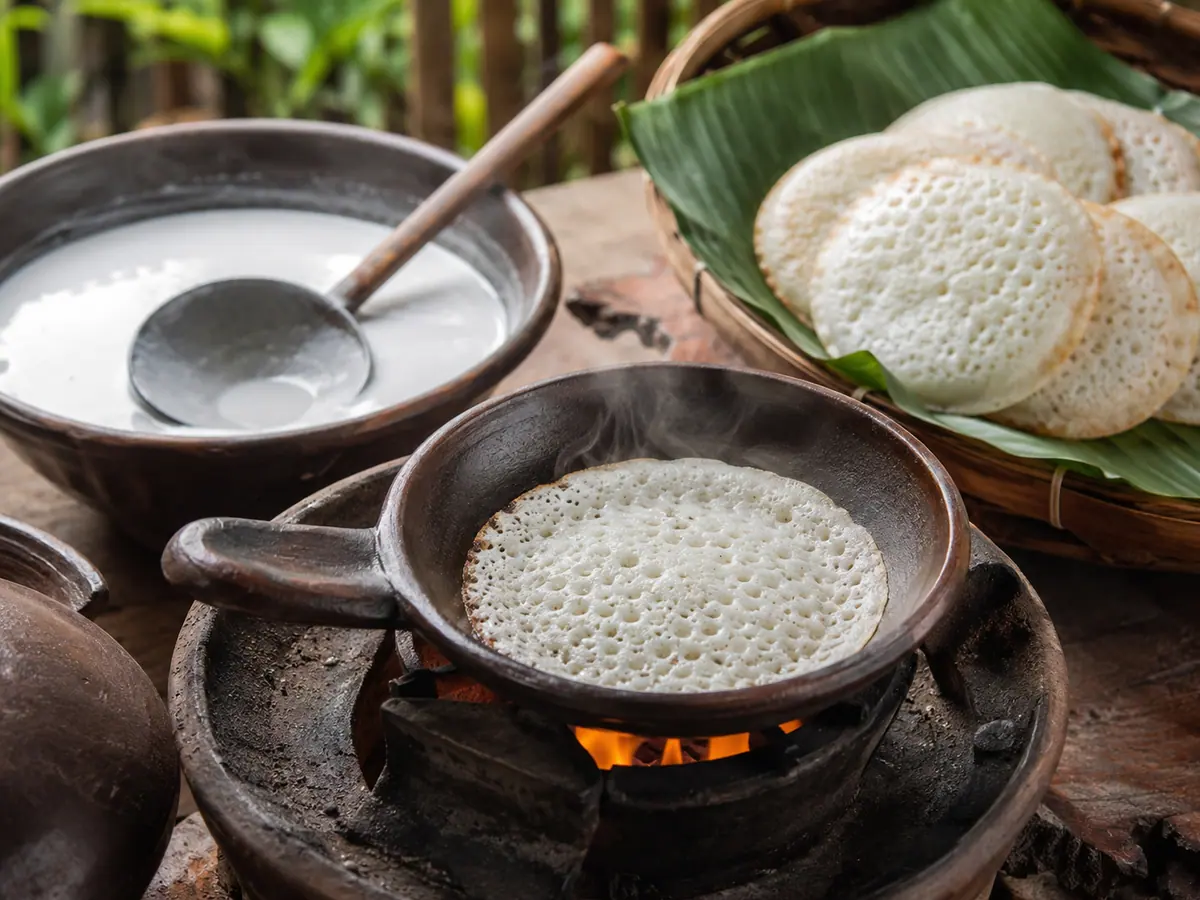 Proses memasak serabi Solo di wajan tanah liat kecil di atas api dengan permukaan berlubang