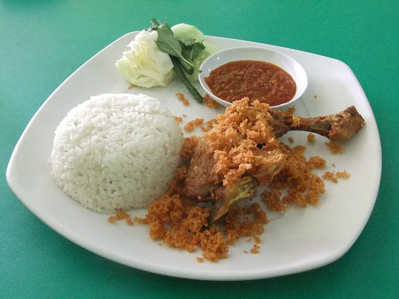 Paket ayam goreng kalasan dengan nasi putih, kremesan, sambal, dan lalapan kol di piring putih