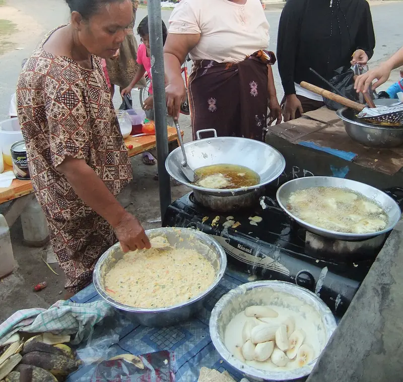 Pedagang mengambil adonan bakwan dari baskom untuk dimasukkan ke minyak panas