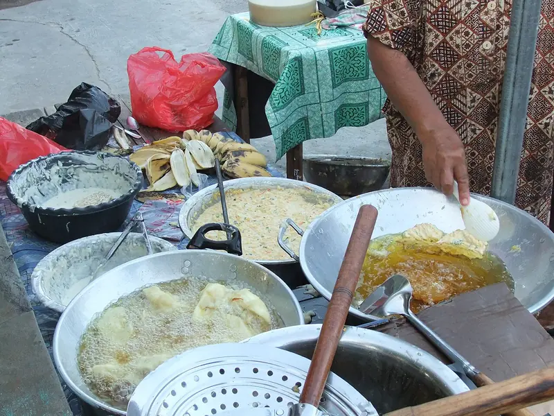 Menggoreng bakwan dalam wajan berminyak banyak di lapak pedagang gorengan