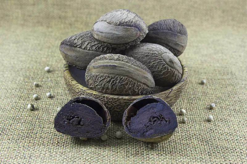 Buah kluwek utuh bercangkang keras dan dua belahan kluwek dengan daging hitam kecokelatan