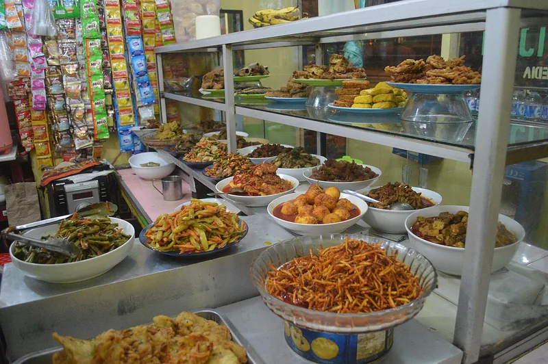 Etalase warteg di Jakarta dengan deretan mangkuk sayur, gorengan, telur balado, dan aneka lauk rumahan