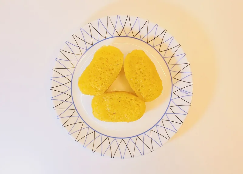 Tiga potong bika ambon kuning keemasan di atas piring putih bermotif garis