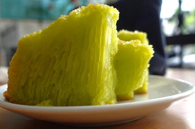 Potongan bika ambon pandan berwarna hijau muda dengan serat berongga di piring putih