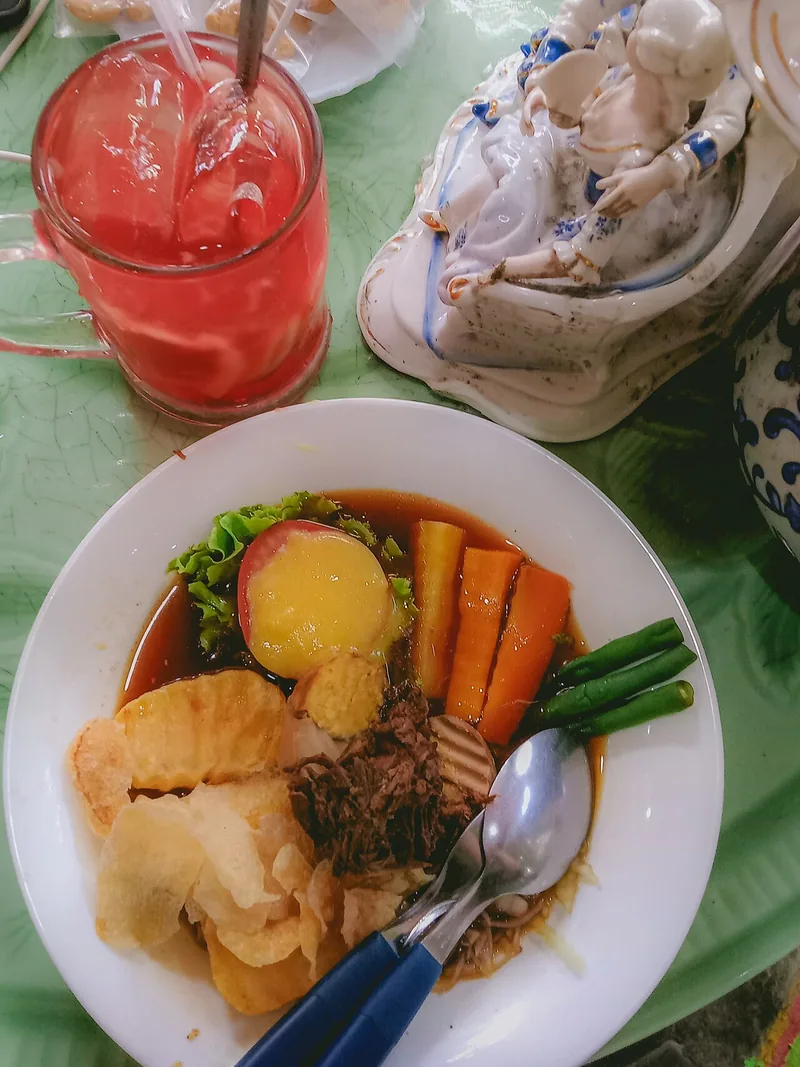 Sepiring selat Solo berisi irisan daging, kentang, wortel, buncis, telur, selada, dan keripik kentang dalam kuah kecap