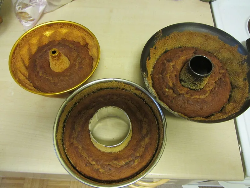Tiga loyang bundar berlubang tengah berisi bolu pisang yang baru keluar dari oven