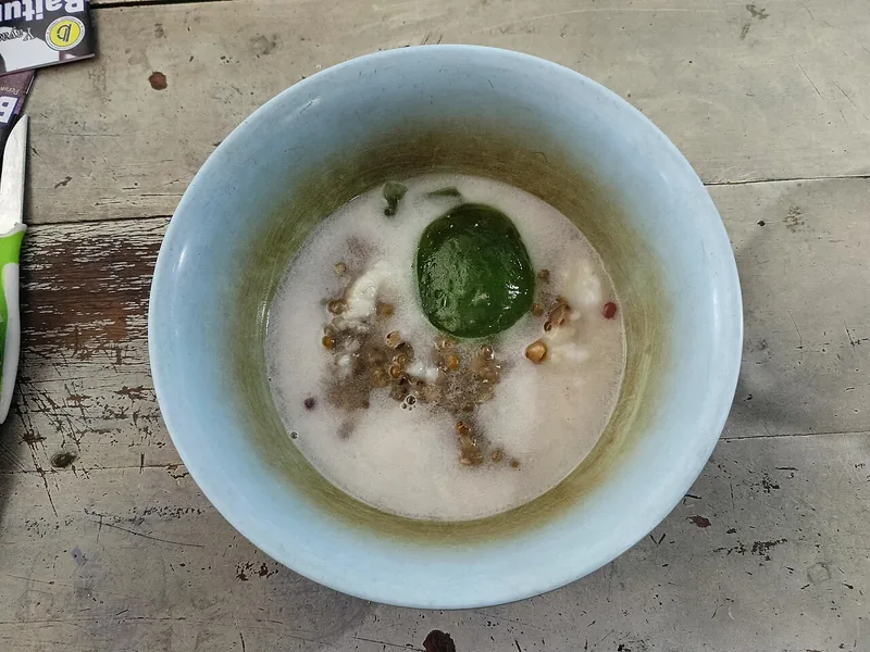 Semangkuk bubur sumsum berkuah santan dengan kacang hijau dan bubur pandan hijau di tengah