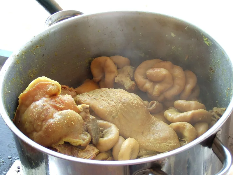 Usus, babat, dan potongan daging sapi direbus dalam panci logam untuk empal gentong