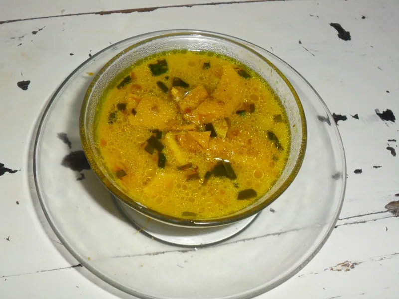 Empal gentong berkuah kuning cerah dengan potongan daging dan kucai dalam mangkuk kaca