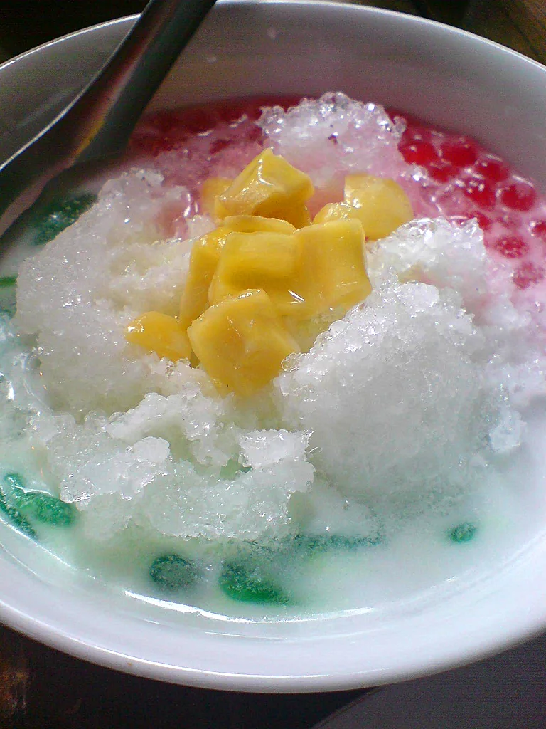 Es campur berisi nangka, cendol hijau, mutiara merah, dan santan di bawah serutan es