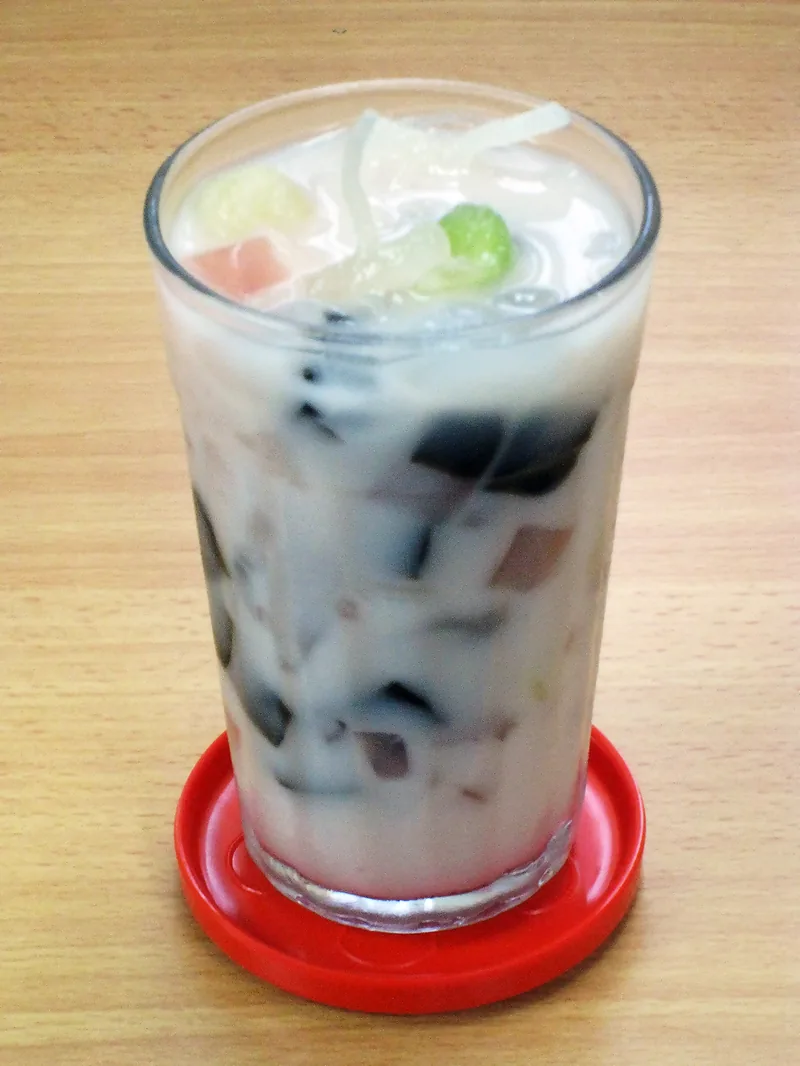 Es campur dalam gelas tinggi berisi cincau hitam, jeli, dan kuah susu putih