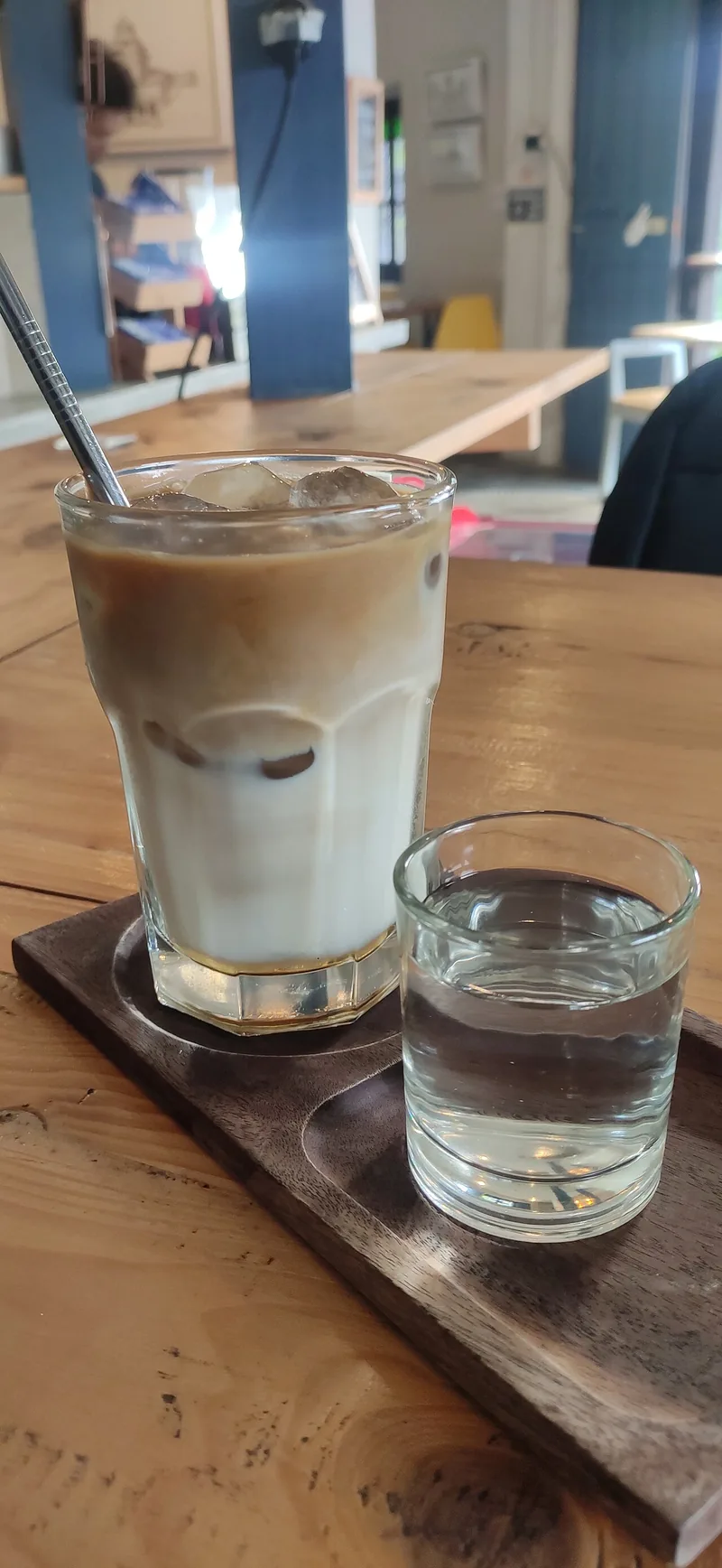 Gelas es kopi susu dengan kopi cokelat di atas susu putih, di samping gelas air putih