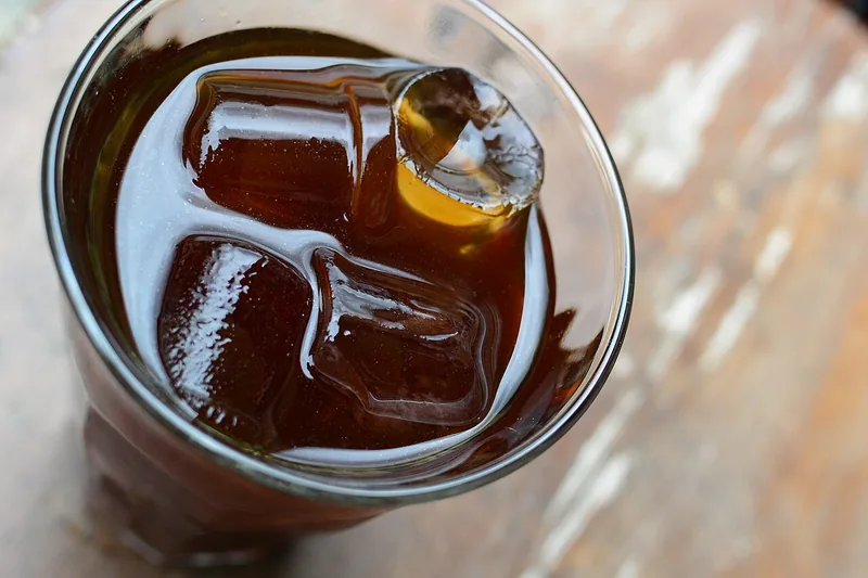 Es kopi cold brew hitam dengan balok es batu besar di dalam gelas plastik bening