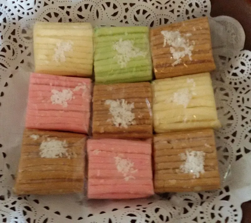 Sembilan potong getuk lindri warna kuning, hijau, merah muda, dan coklat bertabur kelapa