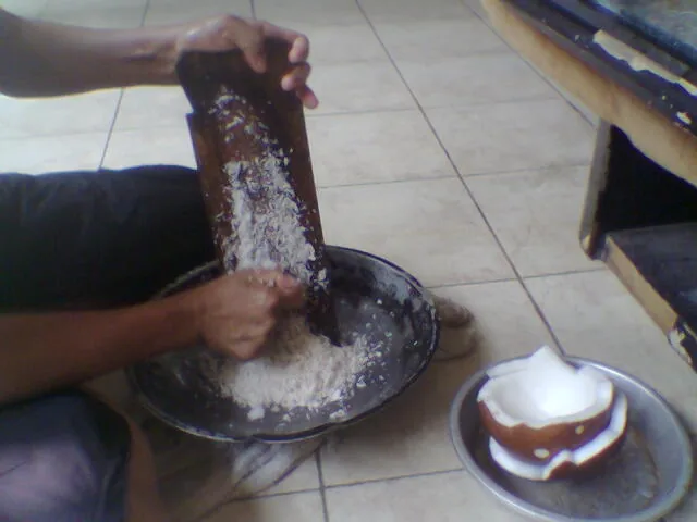 Memarut daging kelapa untuk membuat santan bahan gudeg jogja