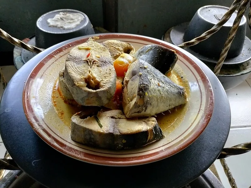Gulai tongkol berkuah santan kuning dengan potongan tebal ikan dan tomat di piring