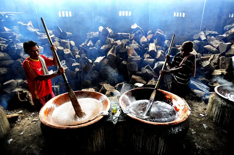 Pekerja mengaduk adonan dodol jenang di kuali besar tanpa berhenti