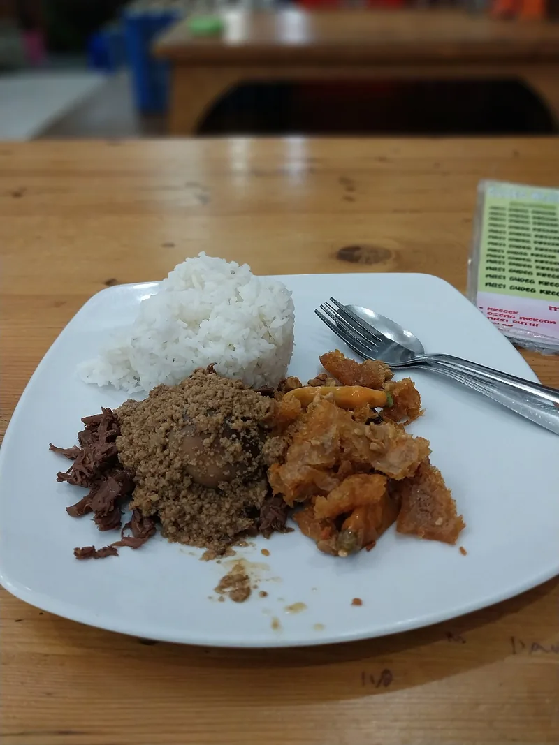 Sepiring nasi putih dengan gudeg, telur pindang, suwiran ayam, dan sambal krecek di Wijilan Yogyakarta