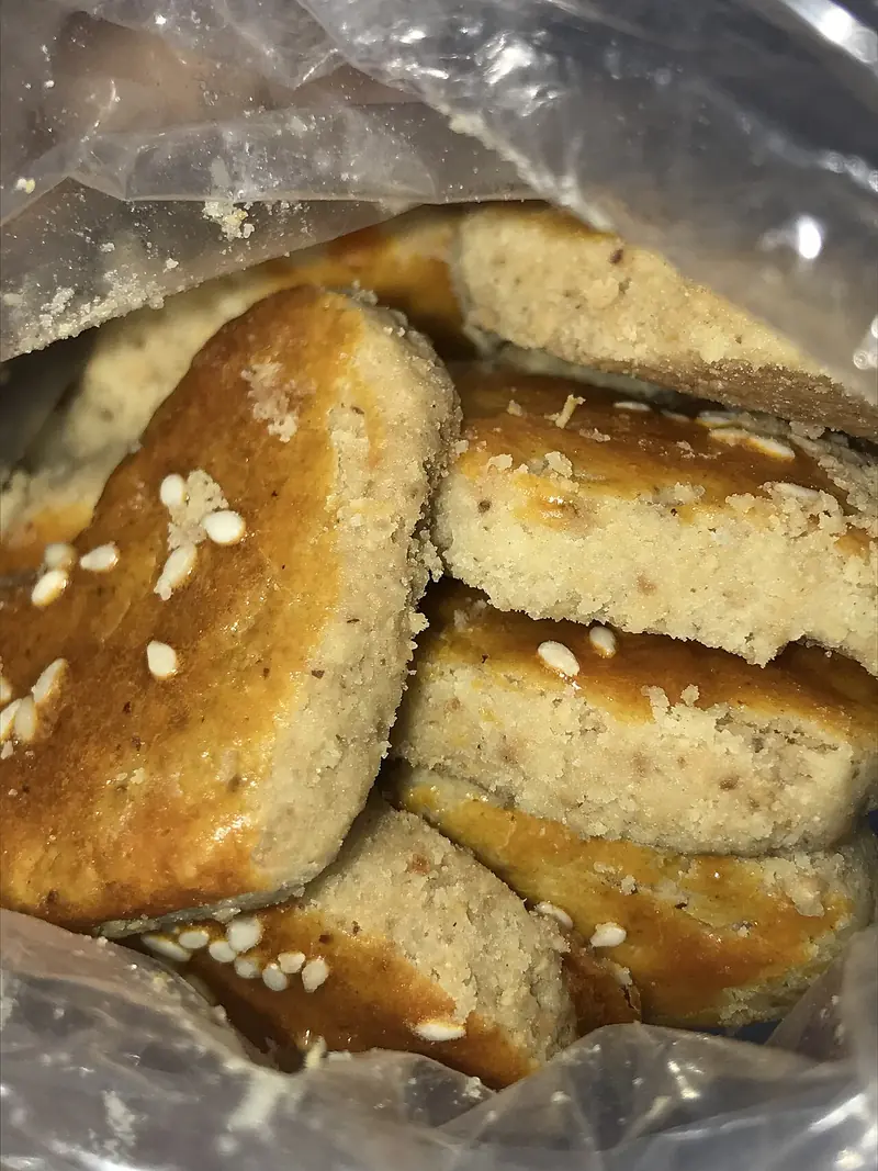 Kue kacang berbentuk kotak dengan taburan wijen di dalam kantong plastik